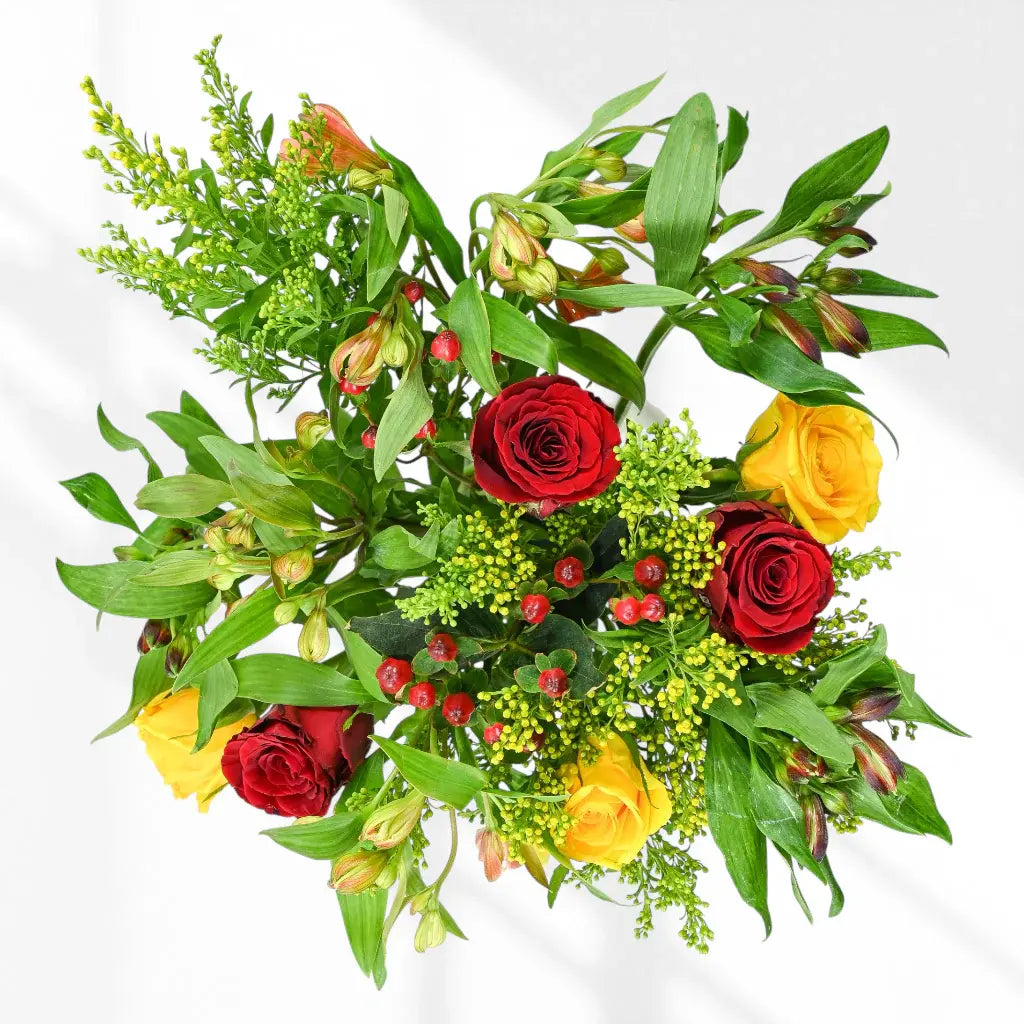 Aerial view red roses, yellow roses, green solidago, orange alstroemeria stems, red berry clusters